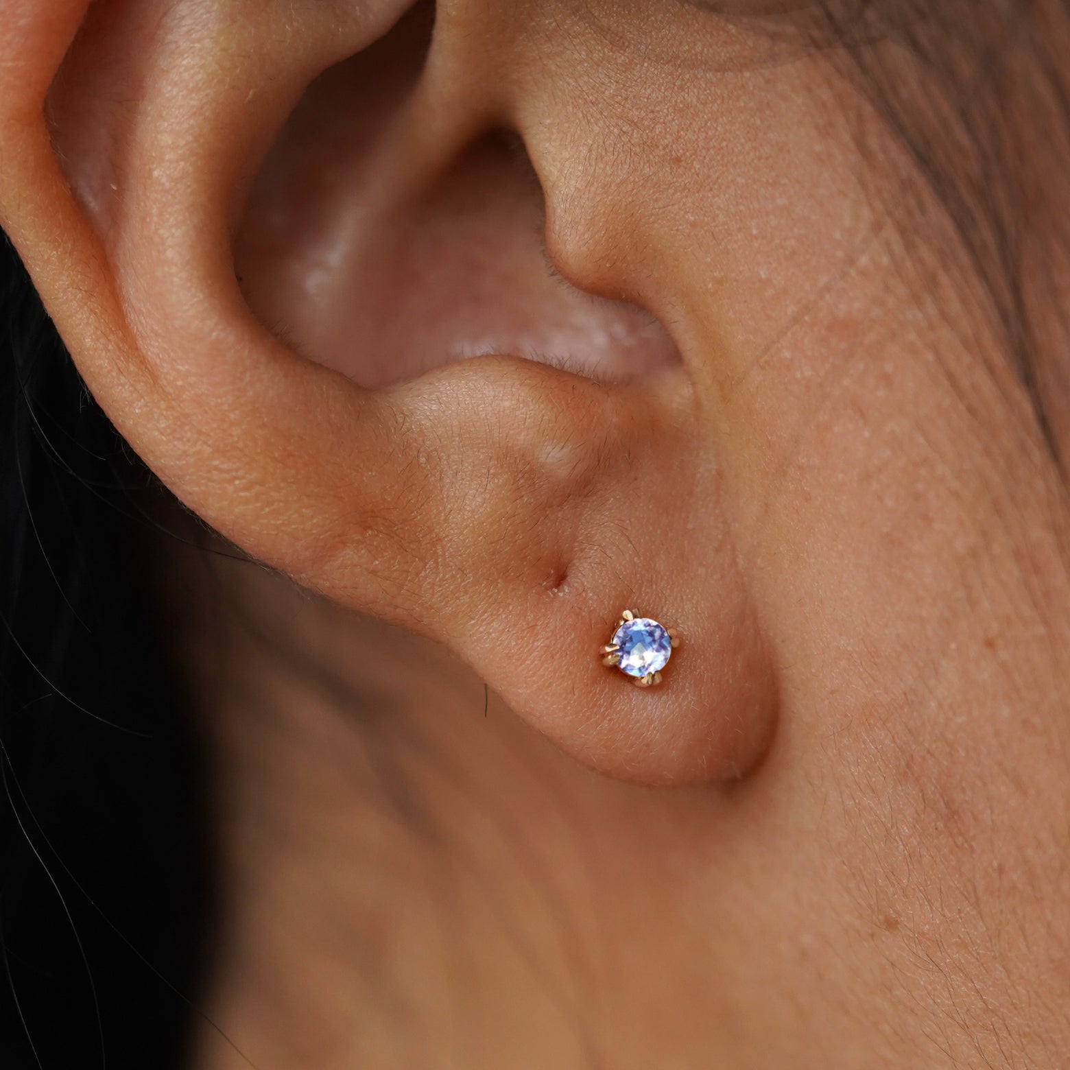 Close up view of a model's ear wearing a 14k yellow gold Aquamarine Earring