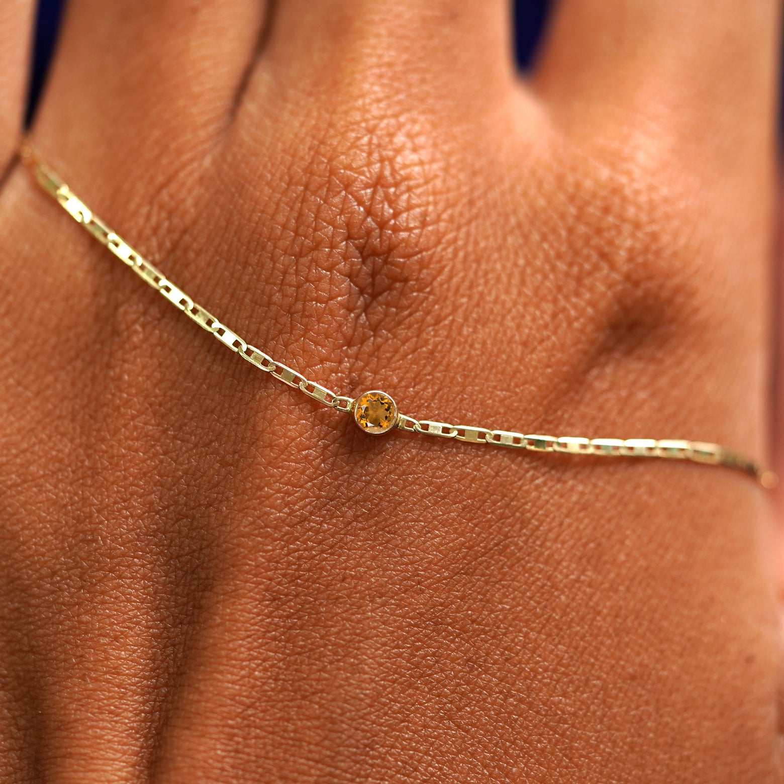 A solid gold Citrine Bracelet resting on the back of a model's hand