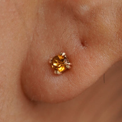 Close up view of a model's ear wearing a 14k yellow gold Citrine Stud Earring