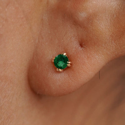 Close up view of a model's ear wearing a 14k yellow gold Emerald Earring