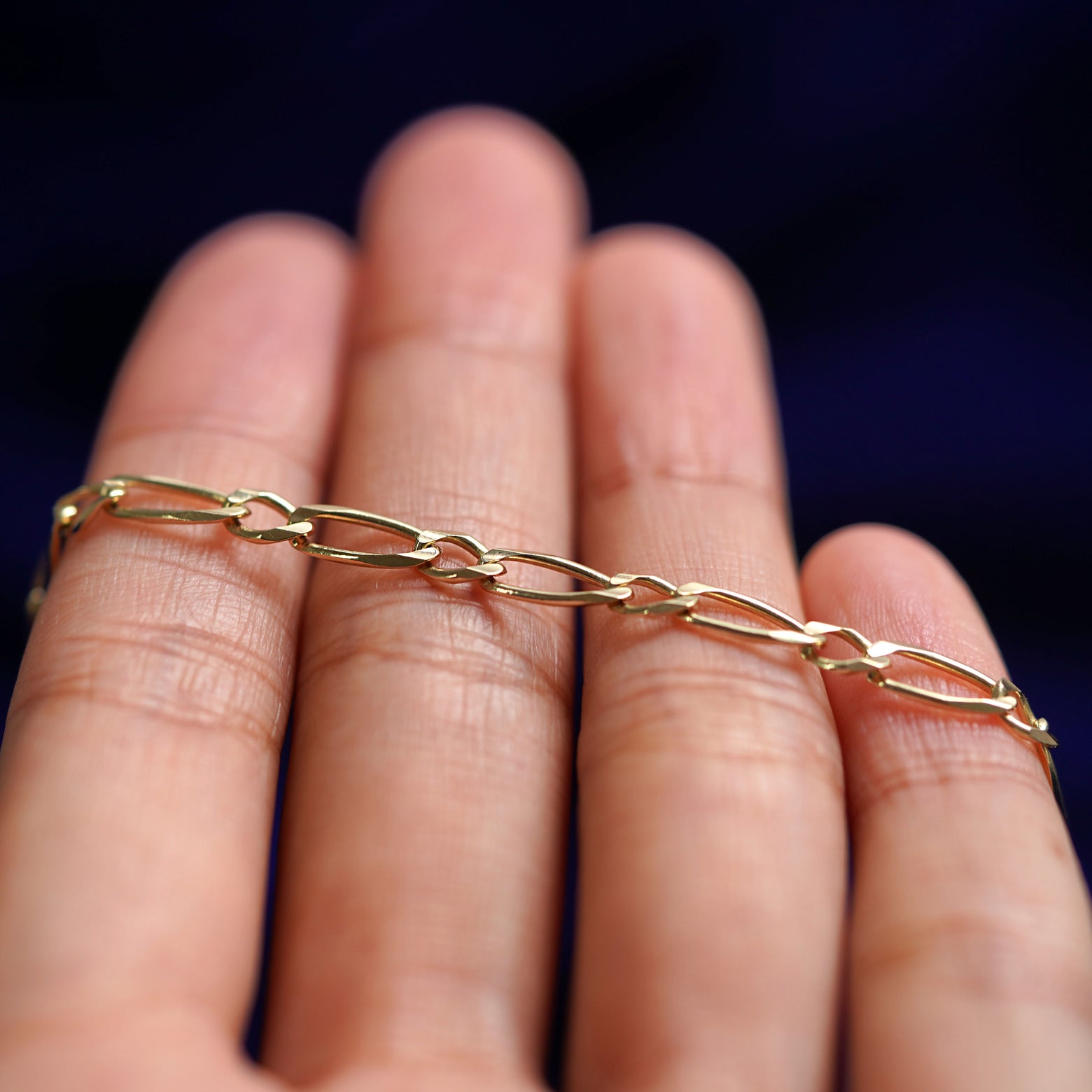 A yellow gold One to One Chain resting on a model's fingers