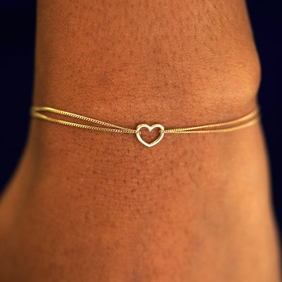 A model's wrist wearing a solid yellow gold Heart Bracelet
