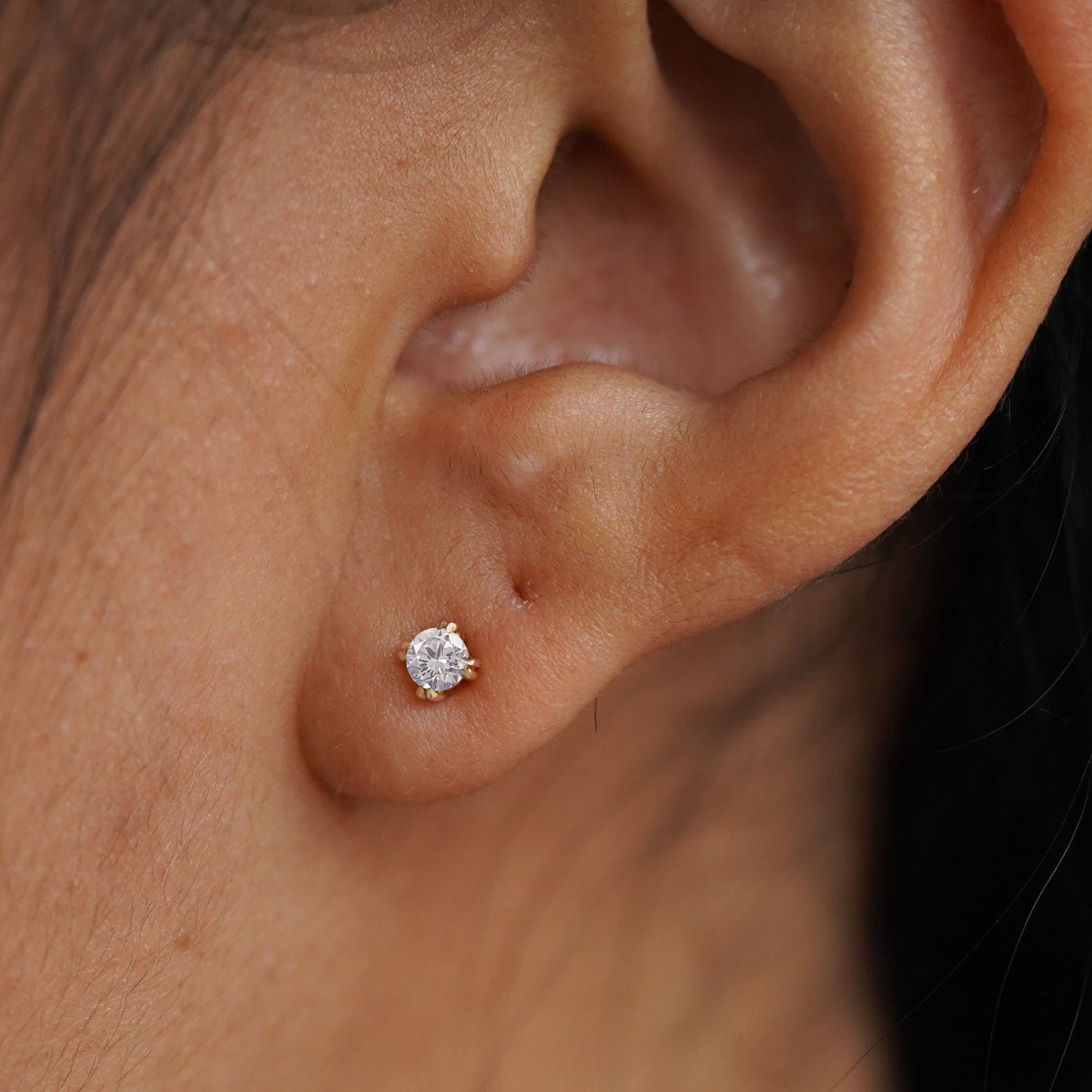 A model's ear wearing a 14k gold Moissanite Earring