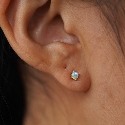 A model's ear wearing a 14k gold Opal Earring