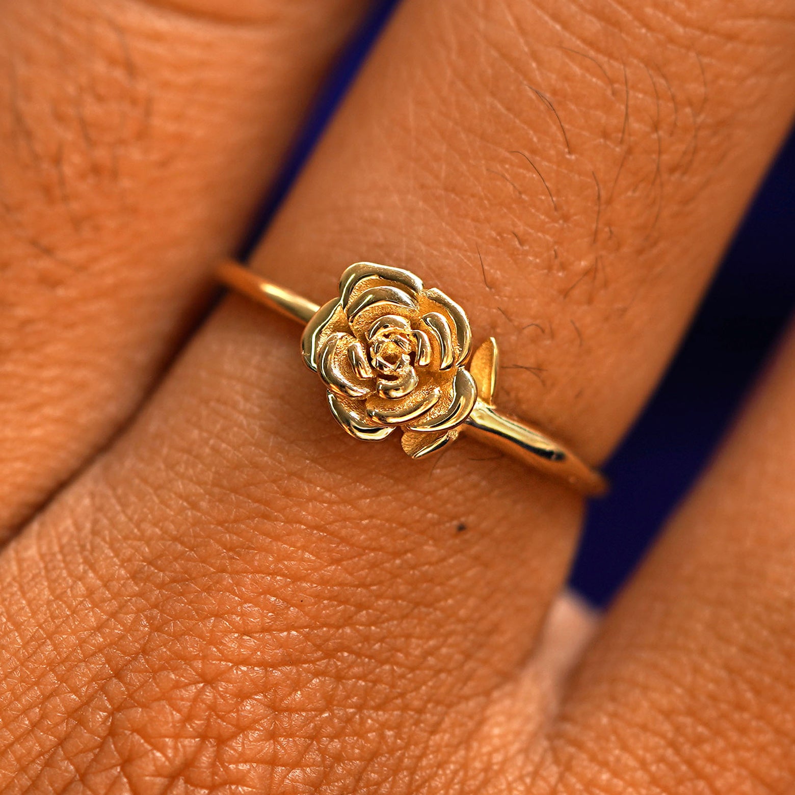 Close up view of a model's hand wearing a solid gold Rose Ring