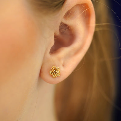A model's ear wearing a 14k gold Rose Earring
