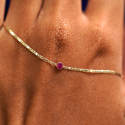 A solid gold Ruby Bracelet resting on the back of a model's hand