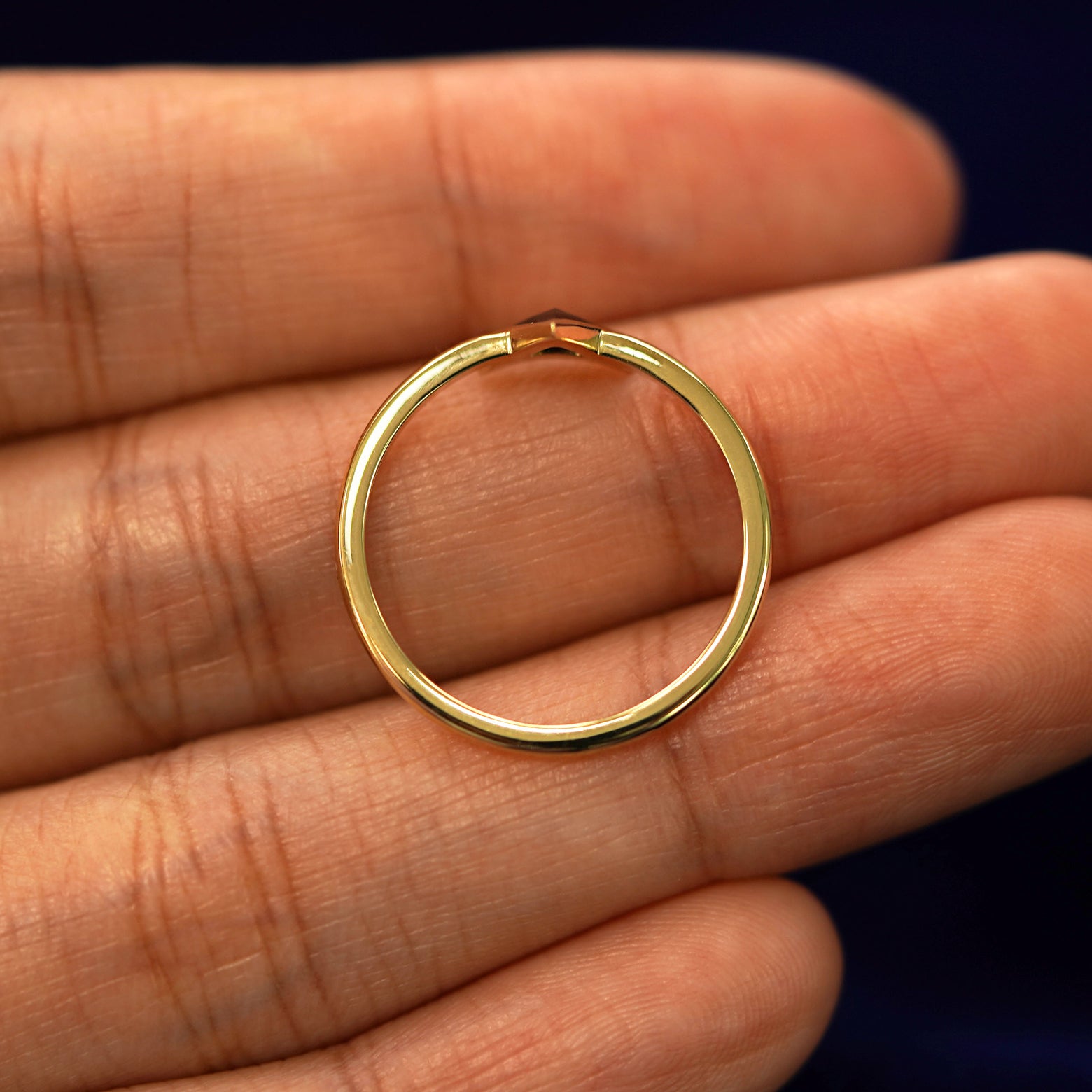 A yellow gold Trillion Black Diamond Ring in a model's hand showing the thickness of the band