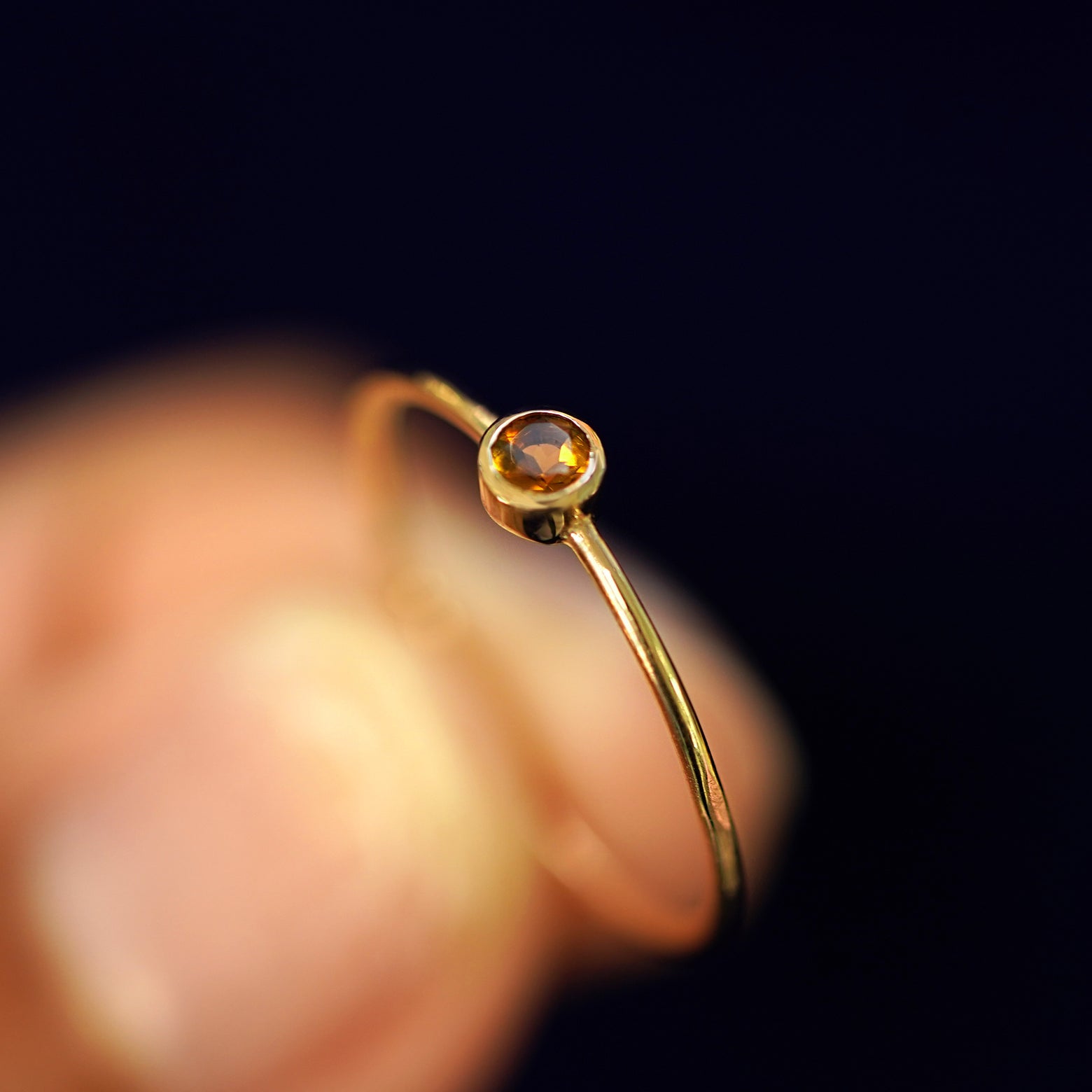 A model holding a Citrine Ring tilted to show the bezel setting