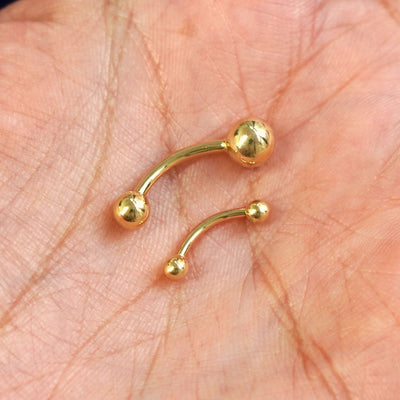 Small and Large Curved Barbell Piercings shown next to each other for size comparison in a model's hand