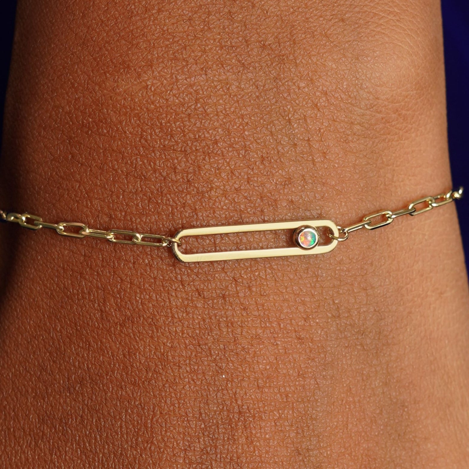 Close up view of a model's wrist wearing a yellow gold Dancing Gemstone Bracelet with a single Opal