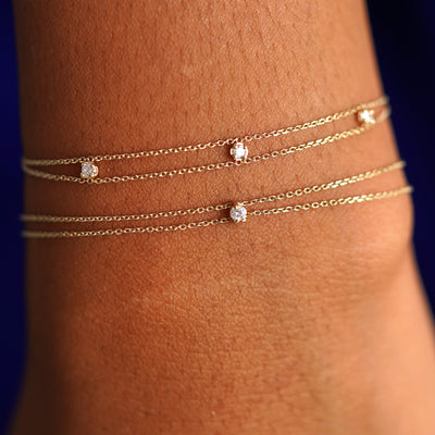 A model's wrist wearing a 3 diamond cable bracelet and a diamond cable bracelet layered 