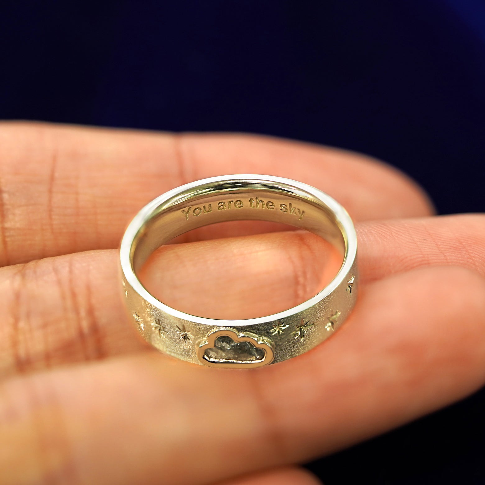 A white gold Cloud Diamond Band in a model's hand engraved with the words You Are the Sky