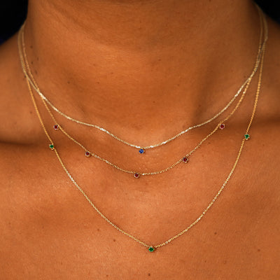 A model wearing a sapphire cable necklace, a 5 ruby cable necklace, and a 3 emerald cable necklace layered 
