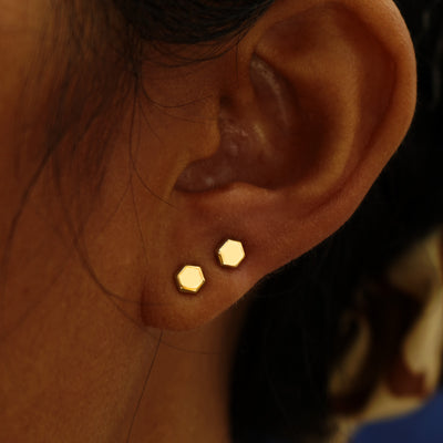 A model's ear wearing a pair of Hexagon stud earrings in two different lobe piercings on the same ear