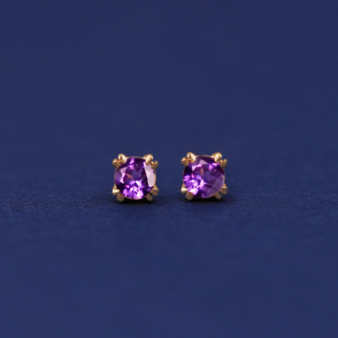 A pair of 14 karat gold studs earrings with 3 millimeter round Amethyst gemstones