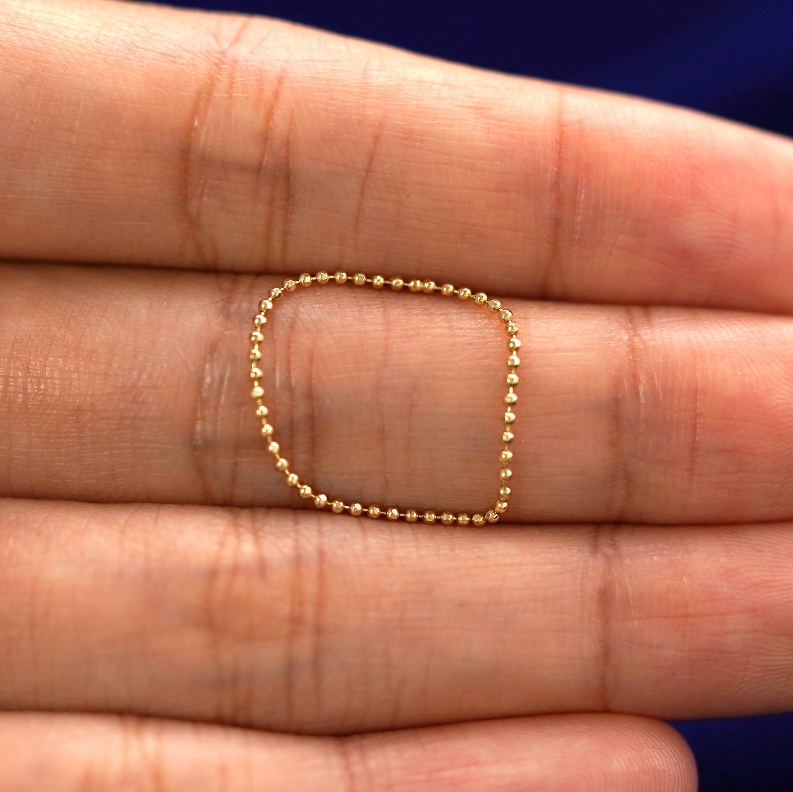 A yellow gold Bead Chain Ring in a model's hand showing the thickness of the chain