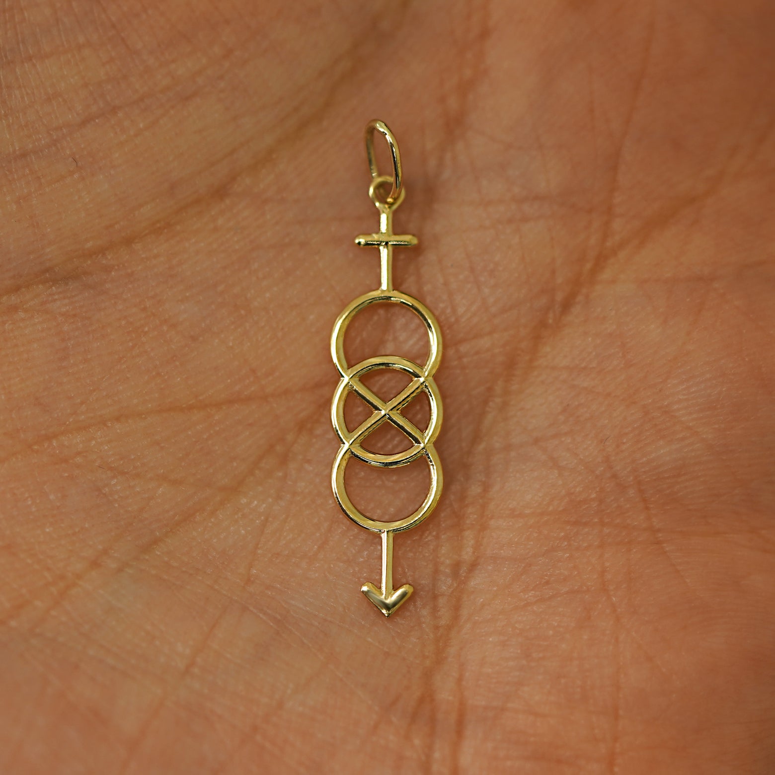 A solid gold Bisexual Symbol Charm for chain resting in a model's palm