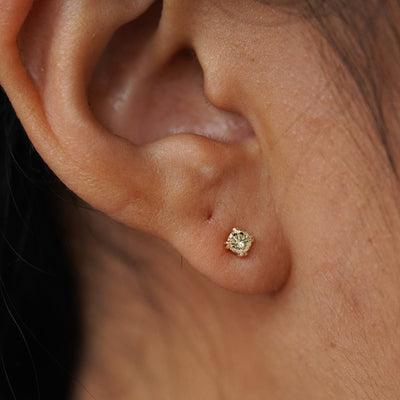 Close up view of a model's ear wearing a 14k yellow gold Champagne Diamond Earring