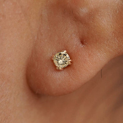 Close up view of a model's ear wearing a 14k yellow gold Champagne Diamond Stud Earring