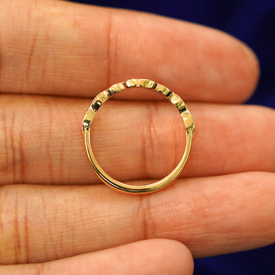 A yellow gold Chevron Leaves Band in a model's hand showing the thickness of the band