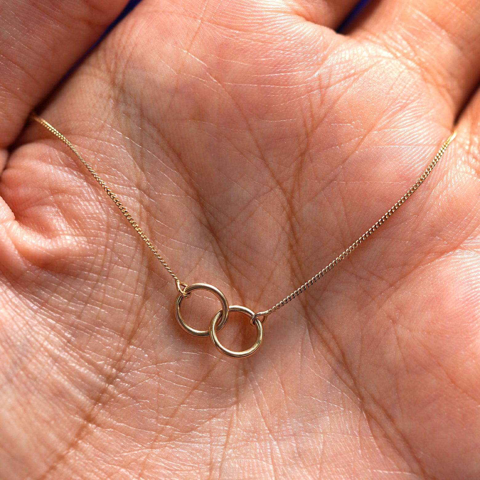 A yellow gold Mini Bound Together Bracelet draped on a model's palm