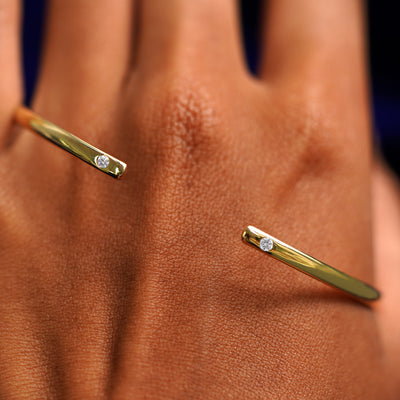 A solid gold Diamond Open Bangle Bracelet resting on the back of a model's hand