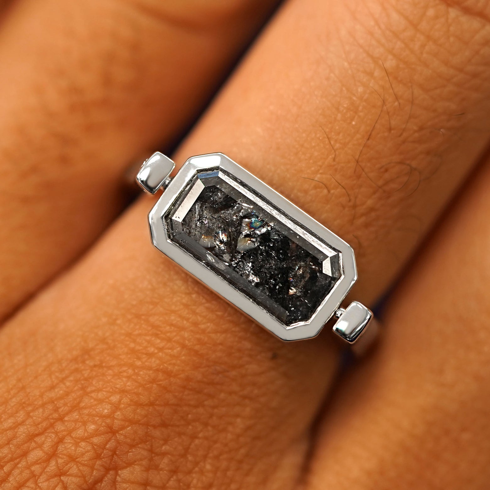 Close up view of a model's fingers wearing a 14k white gold Salt and Pepper Diamond Spinner Ring