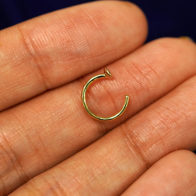A 14k yellow gold Diamond Open Hoop resting flat on a models fingertips to show the thickness of the earring
