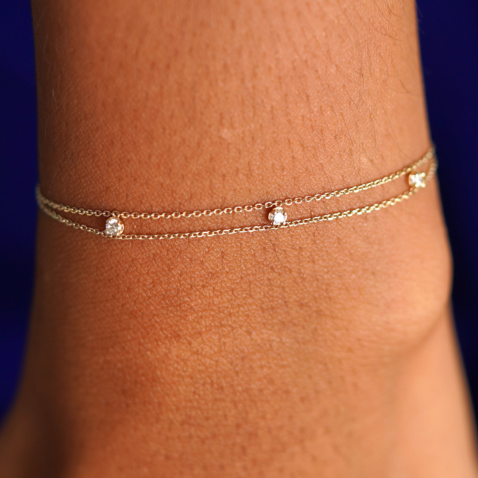 Close up view of a model's wrist wearing a solid yellow gold 3 Diamond Cable Bracelet