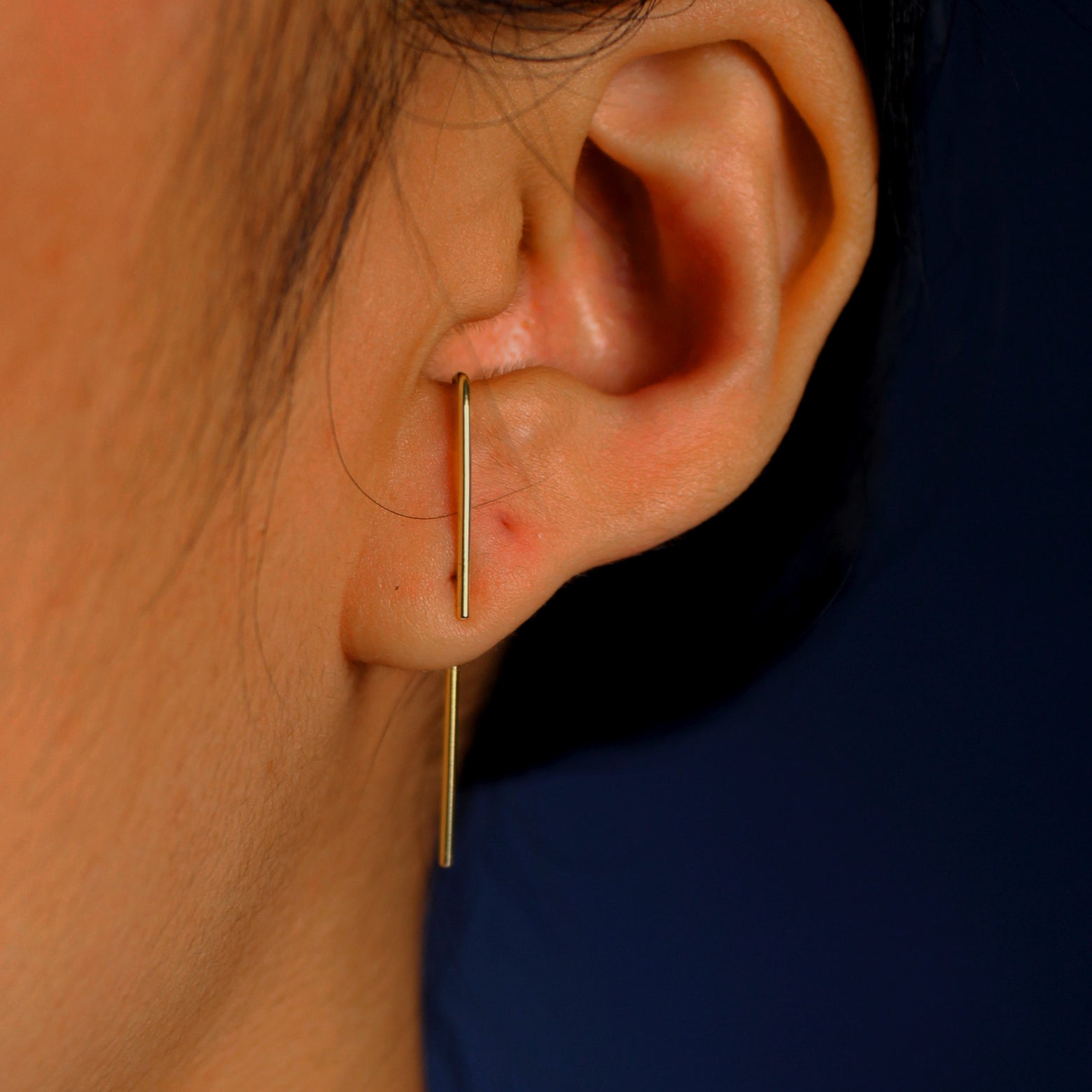 A model's ear wearing a 14k yellow gold Line Jacket with a Suspender Earring