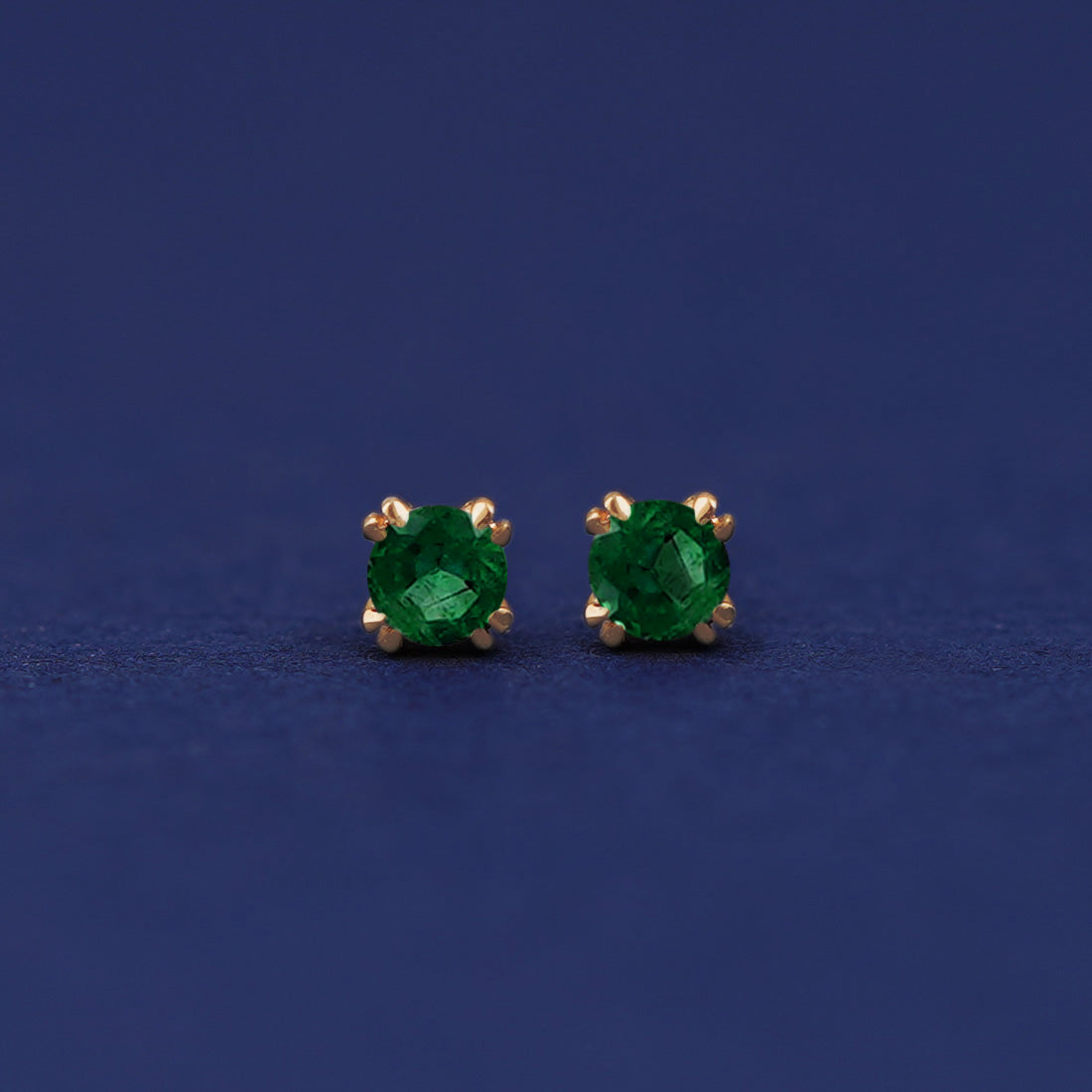 A pair of 14 karat gold studs earrings with 3 millimeter round Emerald gemstones