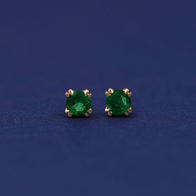 A pair of 14 karat gold studs earrings with 3 millimeter round Emerald gemstones