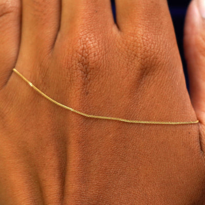 A solid gold Essential Bracelet resting on the back of a model's hand