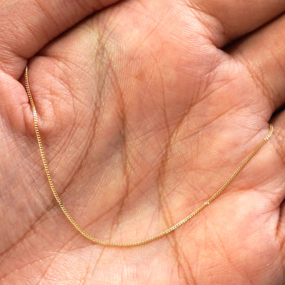 A yellow gold Essential Bracelet draped on a model's palm