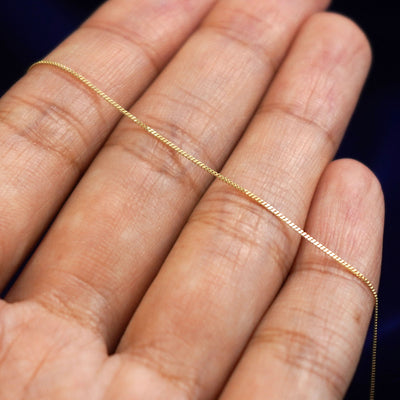 A yellow gold Essential Chain resting on a model's fingers