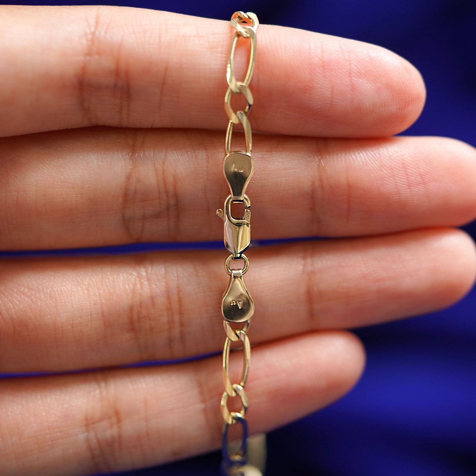 A model holding a 14k yellow gold One to One Bracelet to show the lobster claw clasp