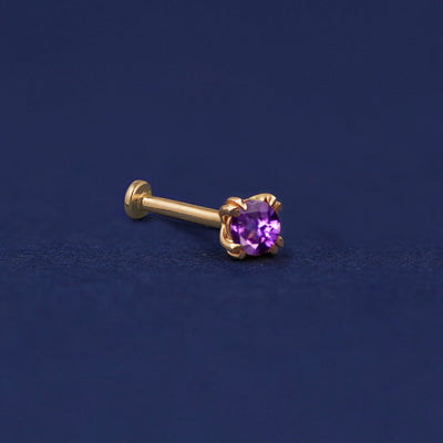 A 14 karat solid gold Amethyst Flat Back Earring on a dark blue background