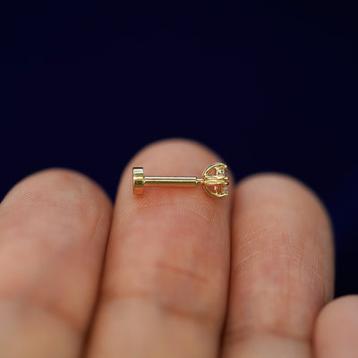 Side view of a yellow gold Moissanite Flatback Piercing on a model's fingertips