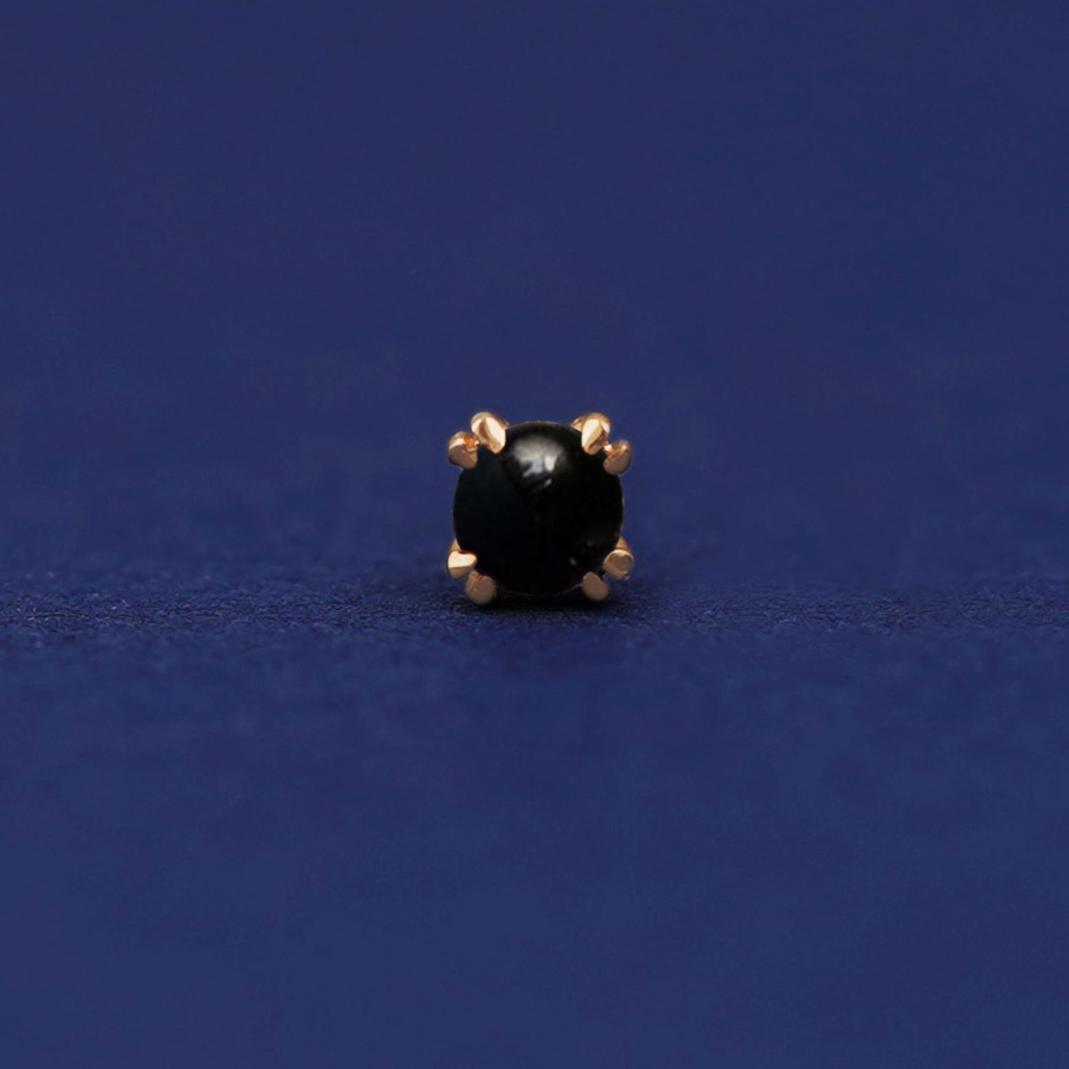 Front facing view of a 14k yellow gold Onyx Flat Back Earring on a dark blue background