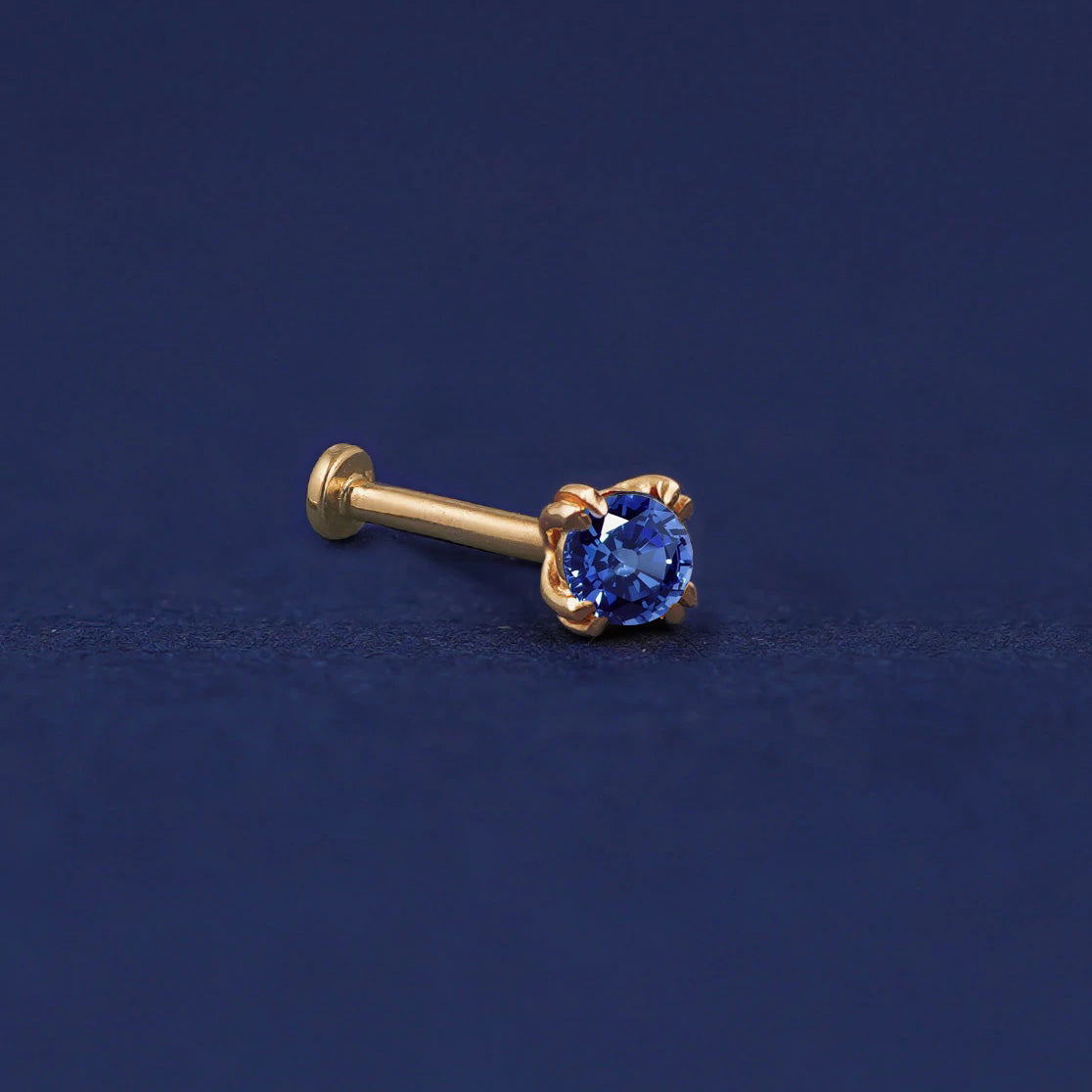 A 14 karat solid gold Sapphire Flat Back Earring on a dark blue background