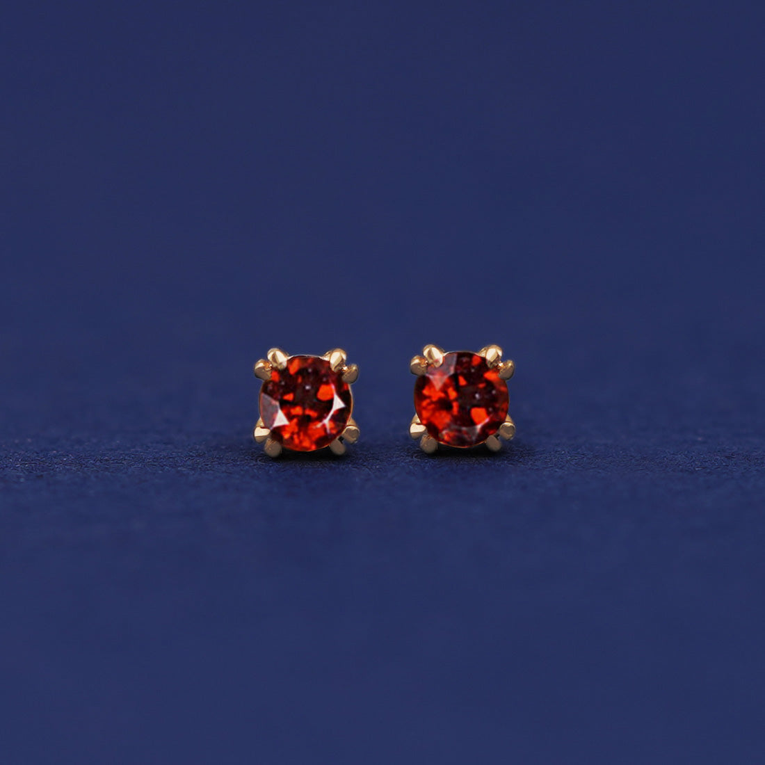 A pair of 14 karat gold studs earrings with 3 millimeter round Garnet gemstones