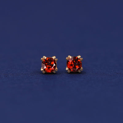 A pair of 14 karat gold studs earrings with 3 millimeter round Garnet gemstones