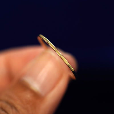 A model holding a Hammered Ring tilted to show the side of the ring