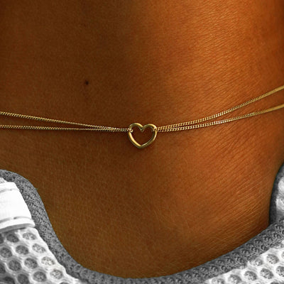 Close up view of a model's ankle wearing a 14k yellow gold Heart Anklet