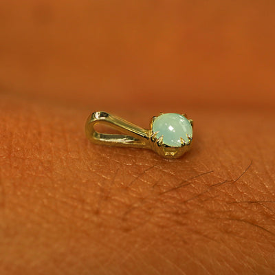 A 14k yellow gold Jade Charm for chain resting on the back of a model's hand