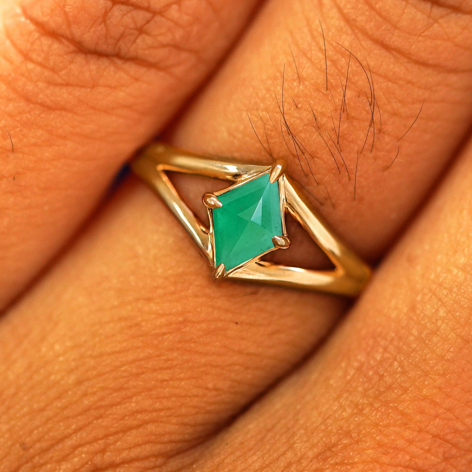 Close up view of a model's fingers wearing a 14k yellow gold Emerald Kite Ring