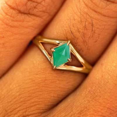 Close up view of a model's fingers wearing a 14k yellow gold Emerald Kite Ring