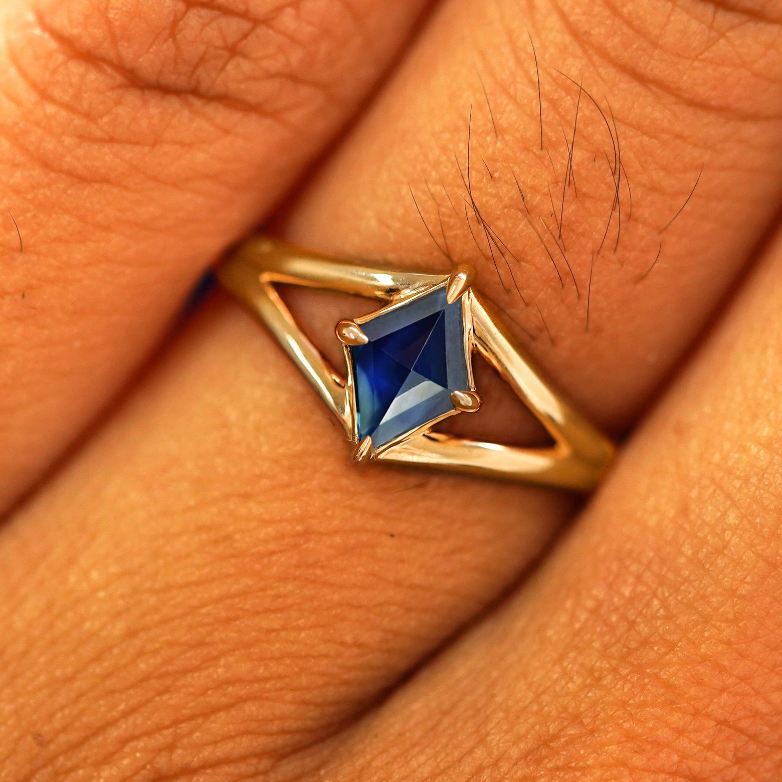 Close up view of a model's fingers wearing a 14k yellow gold Sapphire Kite Ring