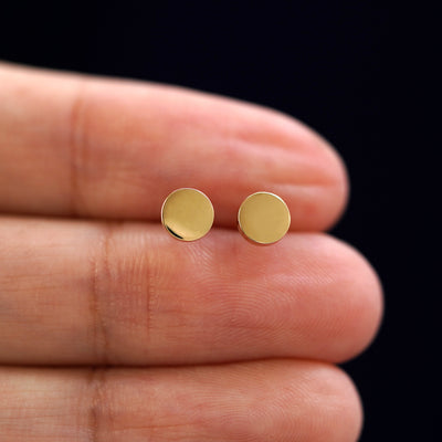 A model's hand holding a pair of recycled 14k gold Large Circle Earrings